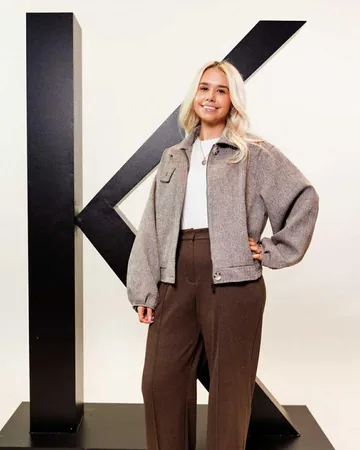 Ami standing in front of the large black Kérastase K, as a Kérastase Care Coach for 2026